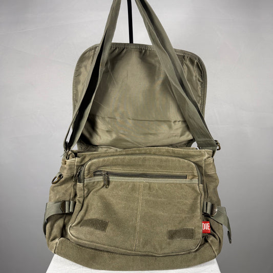 An olive green canvas crossbody bag with multiple front pockets and a top handle, shown open against a neutral gray background.