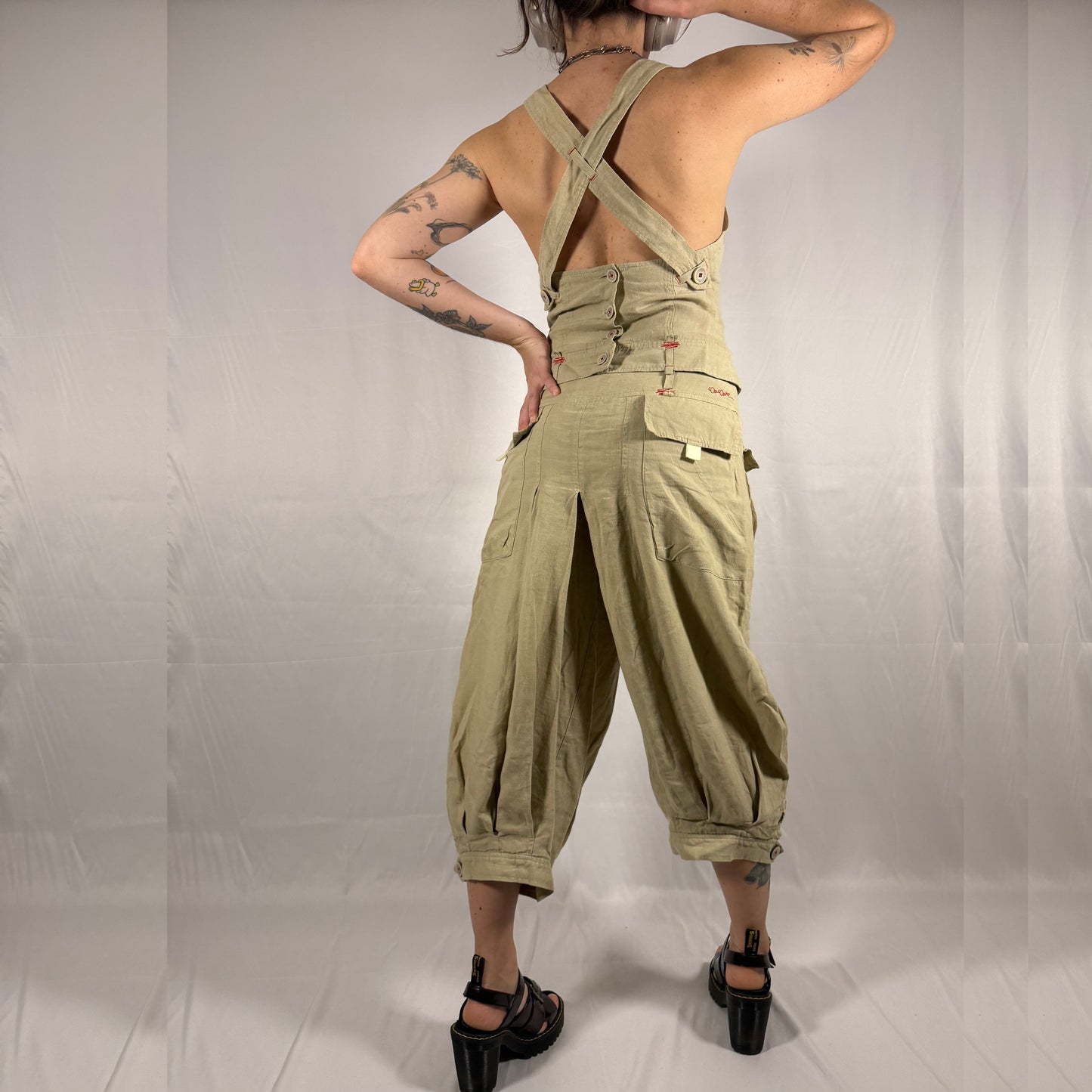 Back view of vintage Cop Copine linen co-ord set showing crossed open-back straps, fitted bodice, and pleated balloon-leg cropped trousers in natural flax linen.
