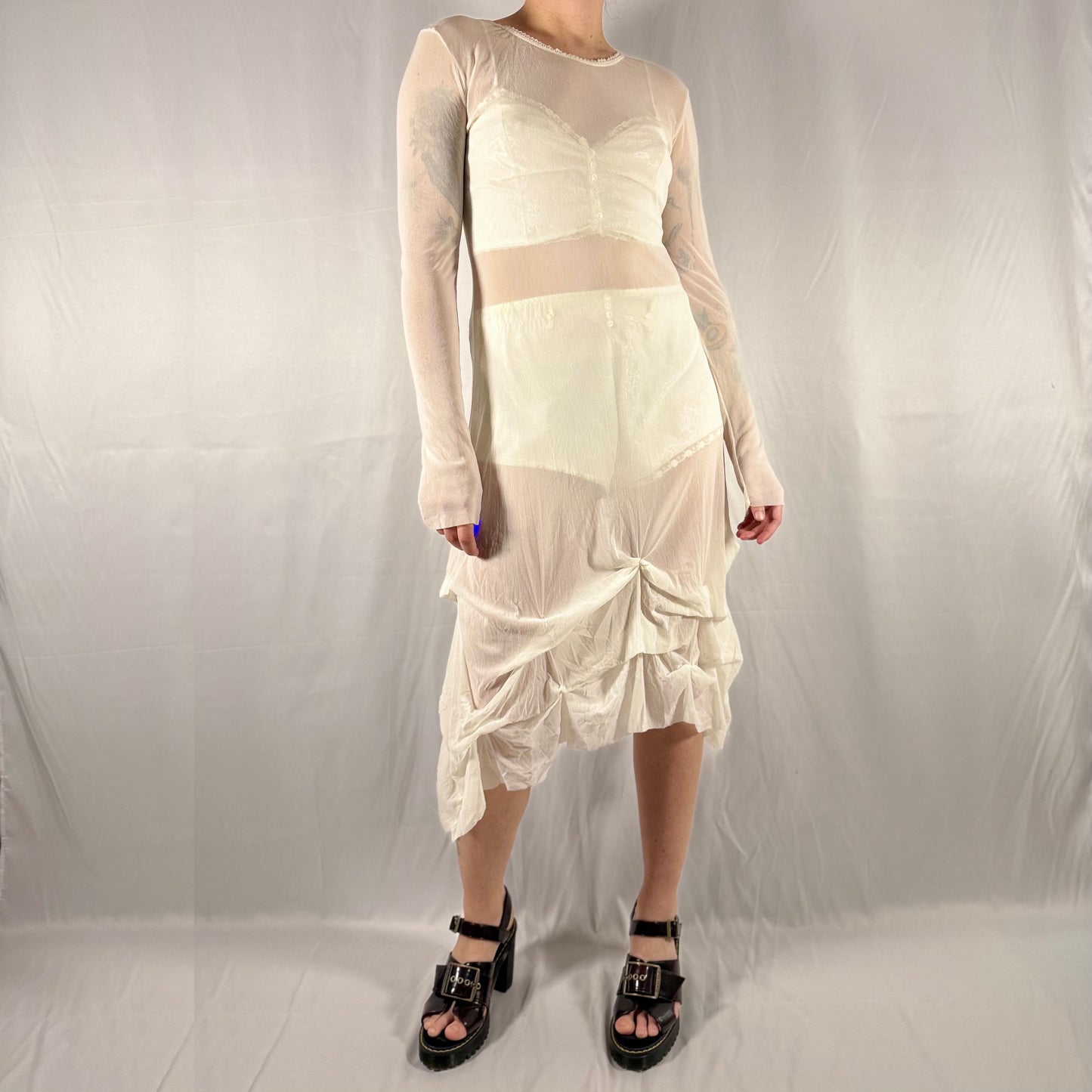 Vintage Y2K Eros Collection sheer white mesh midi dress with lace trim, long sleeves, and asymmetrical gathered skirt styled layered over a cream two-piece set.