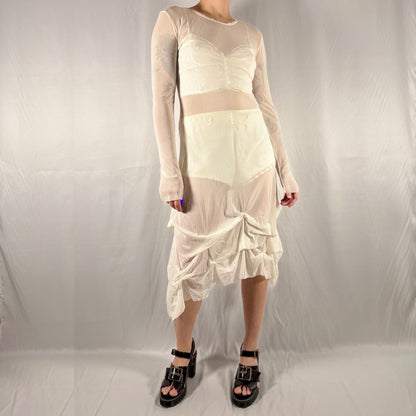 Vintage Y2K Eros Collection sheer white mesh midi dress with lace trim, long sleeves, and asymmetrical gathered skirt styled layered over a cream two-piece set.
