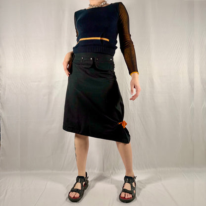 Y2K vintage Cop Copine black asymmetrical cotton utility skirt with detachable snap pockets, orange tie detail, and structured minimalist silhouette