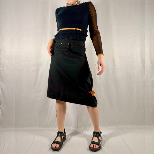 Y2K vintage Cop Copine black asymmetrical cotton utility skirt with detachable snap pockets, orange tie detail, and structured minimalist silhouette