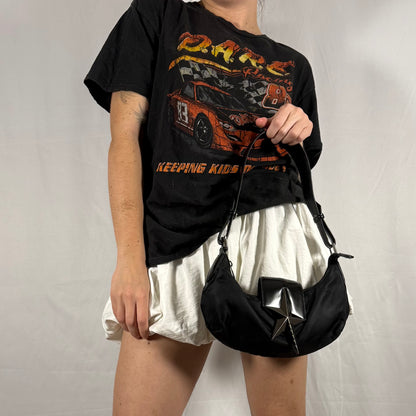 Y2K Thierry Mugler black star baguette bag worn on shoulder, nylon body with patent leather strap and silver star hardware