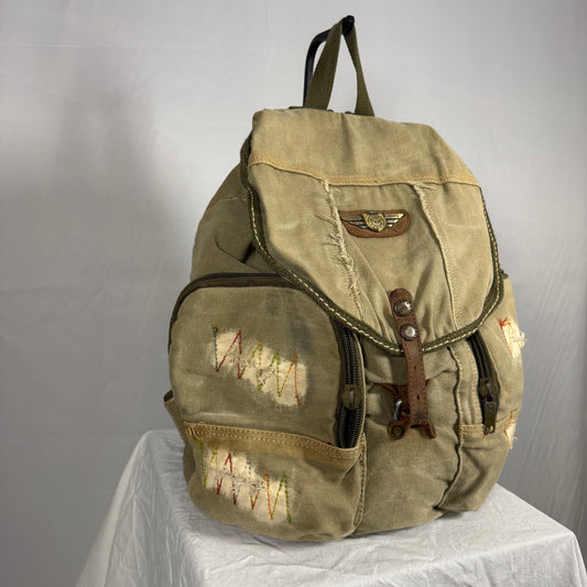 Vintage-style backpack with patches on a gray background