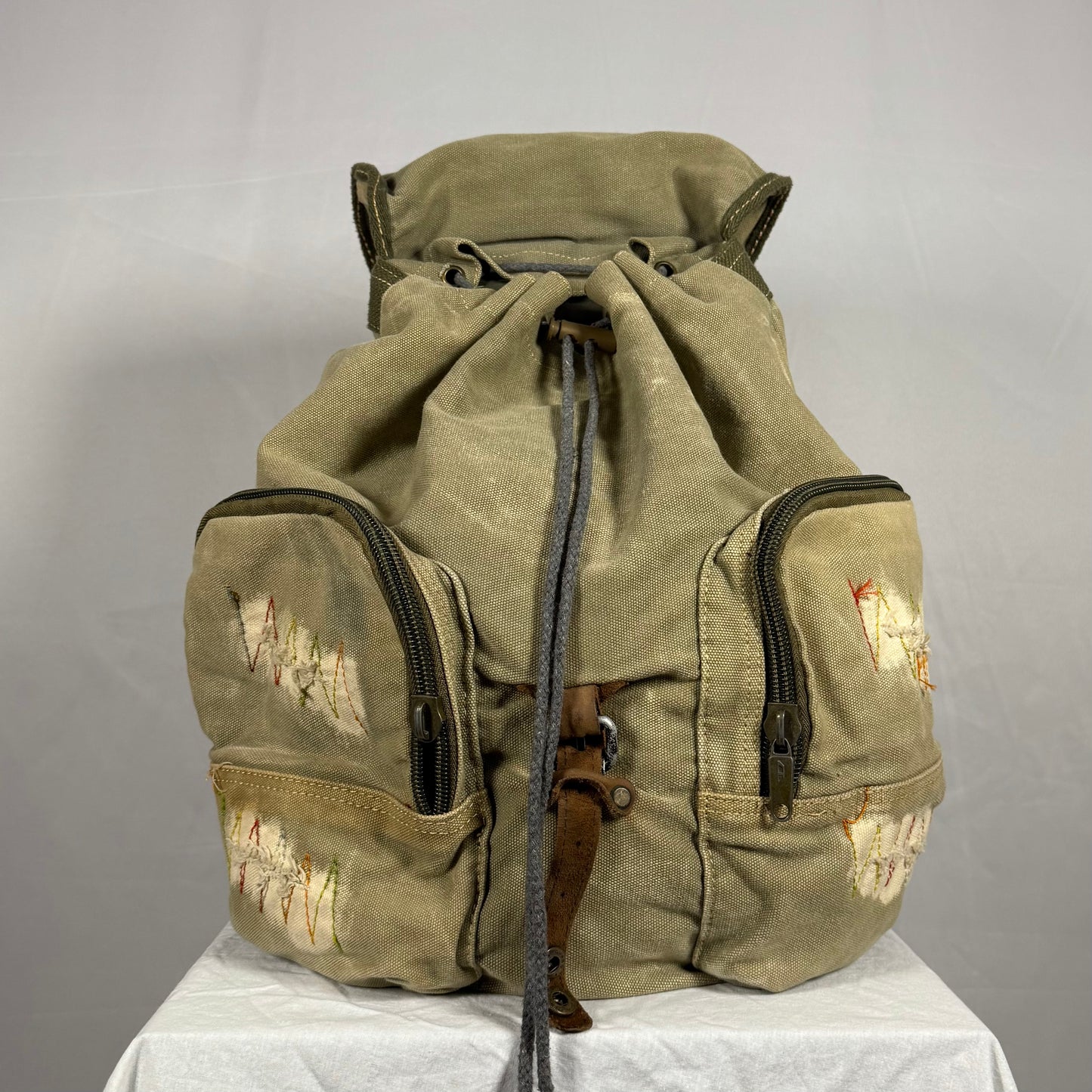 Vintage green backpack with patches on a gray background