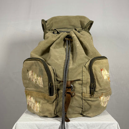Vintage green backpack with patches on a gray background