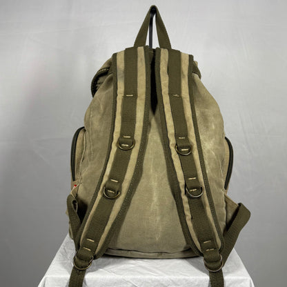 Brown backpack with green straps on a white surface against a gray background