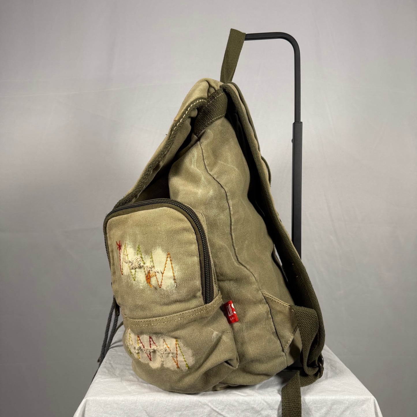 Worn green backpack with visible wear and text on a gray background