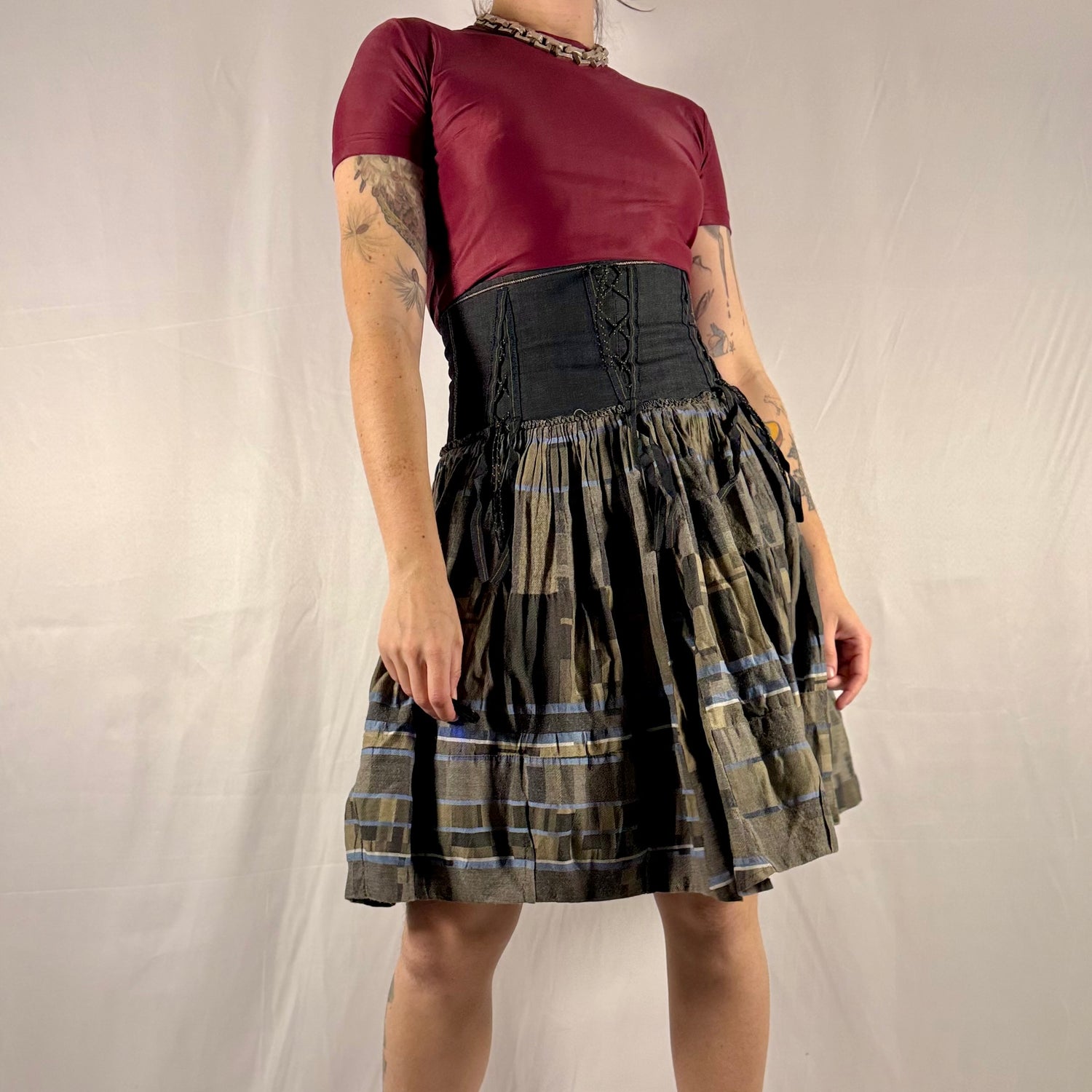 Vintage Y2K Marithé + François Girbaud reversible midi skirt made in Italy featuring a structured black corset waist with lace-up details and a gathered olive plaid cotton skirt.