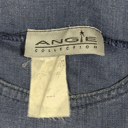 Close-up of a denim garment label reading 'ANGIE COLLECTION' stitched onto blue denim fabric, with a second off-white care tag hanging below.