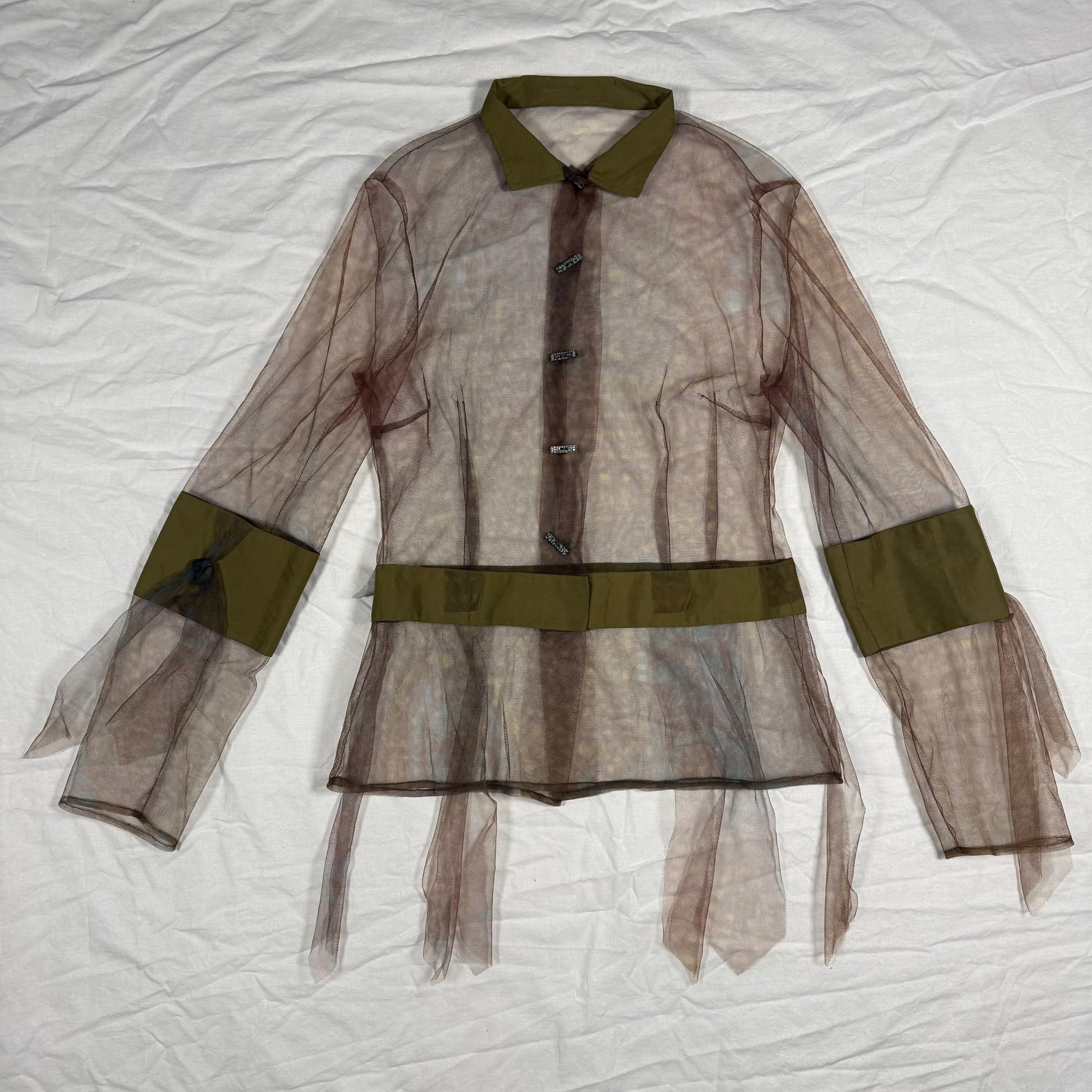 A sheer brown organza tulle blouse with olive green trim on the collar, cuffs, and waist, laid flat on a wrinkled white fabric background.