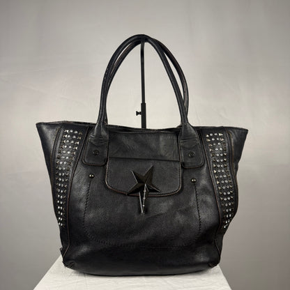 Vintage black Thierry Mugler tote bag with a sculptural star-shaped magnetic front pocket closure, studded side panels, textured exterior, leather detailing, and double shoulder handles.