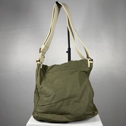 An olive green canvas shoulder bag with a beige strap, displayed on a white surface against a gray background.