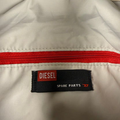 Close-up of a white garment with a red zipper and a black Diesel Spare Parts label.