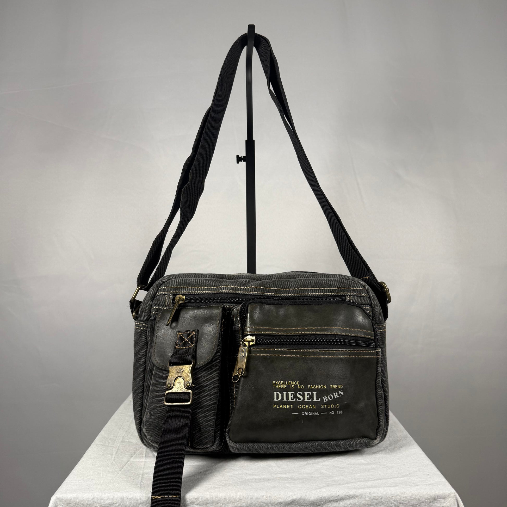 Vintage Y2K Diesel black canvas messenger bag with leather trim, utility pockets, adjustable shoulder strap, and brass hardware.