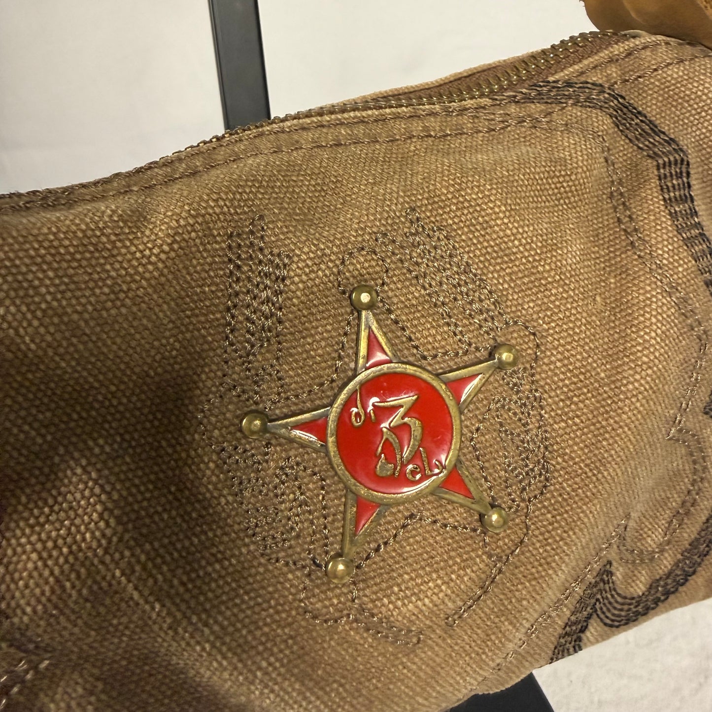Close-up of a brown woven fabric bag featuring a red and gold star-shaped emblem with a stylized symbol in the center.