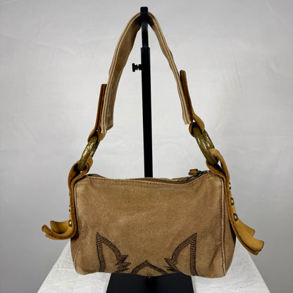 A tan canvas shoulder bag with a wide adjustable strap, displayed on a black stand against a light gray backdrop.