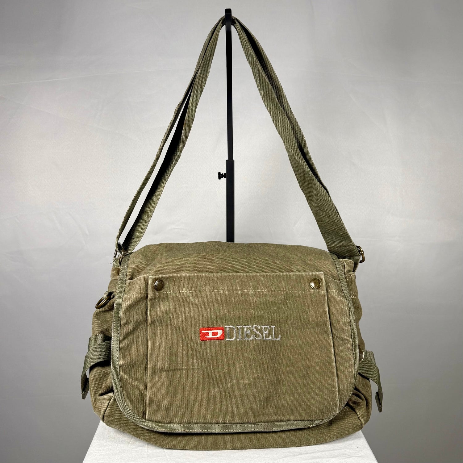 Vintage Diesel olive green heavyweight canvas crossbody bag with embroidered branding, multiple cargo pockets, adjustable shoulder strap and utility details.