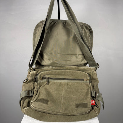 An olive green canvas crossbody bag with multiple front pockets and a top handle, shown open against a neutral gray background.