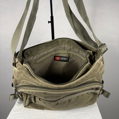An olive green canvas crossbody bag by Diesel, shown open to display its interior compartments, including a zippered pocket and the Diesel brand label inside.
