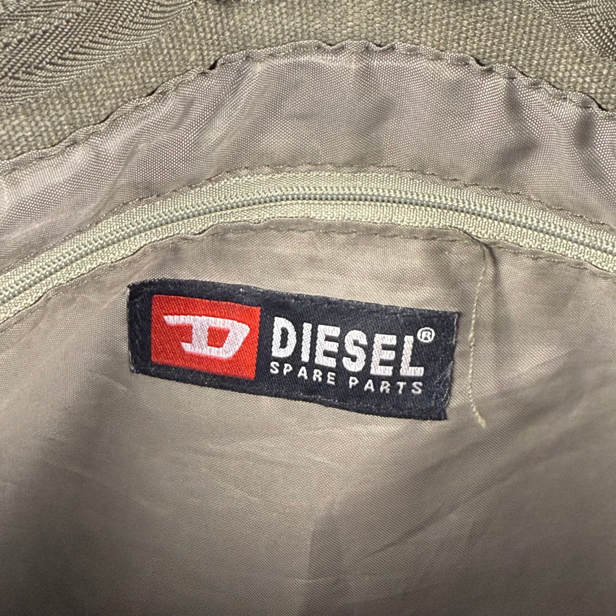 Close-up of a Diesel Spare Parts brand label sewn onto the interior of a beige fabric item.