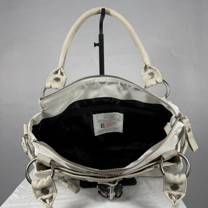 An open white shoulder bag with silver-tone hardware and a black interior lining, photographed from above on a light gray background.