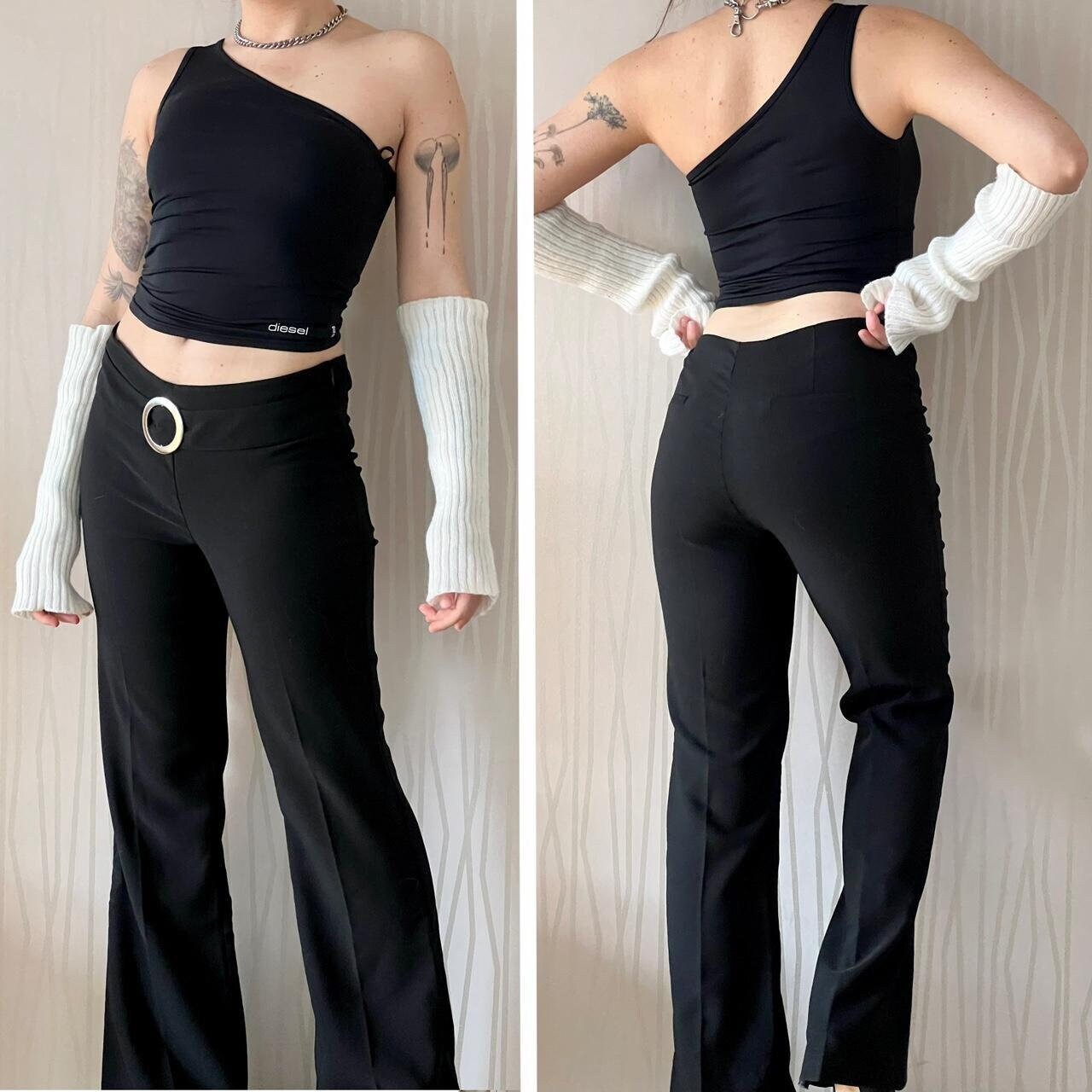 Model wearing black high-waisted flared pants with a large silver ring detail at the waistband, paired with a one-shoulder black top and white knit arm warmers, shown from both front and back views